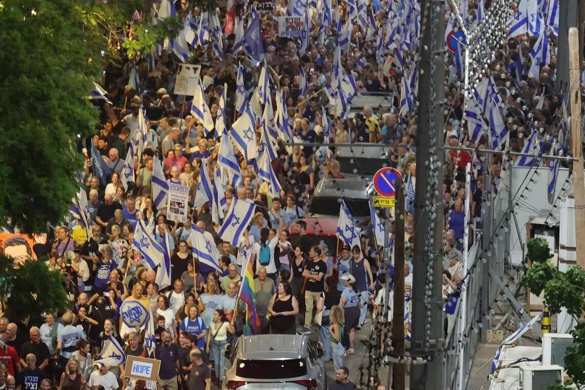 Demonstrators waving national flags and holding banners take part in an anti-government rally in Tel Aviv on Oct 24.