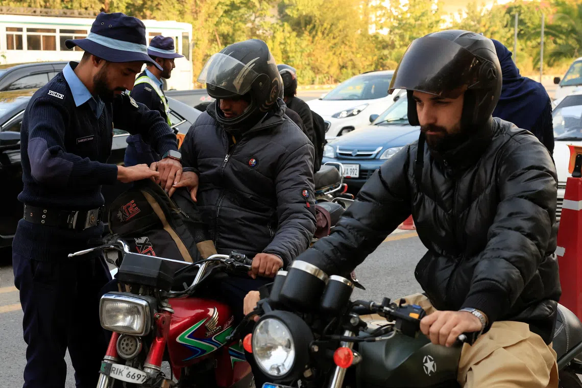 A police officer checks the bag of a biker at a security check post along a road following yesterday's blast outside the district court building, in Islamabad, Pakistan, November 12, 2025. REUTERS/Akhtar Soomro