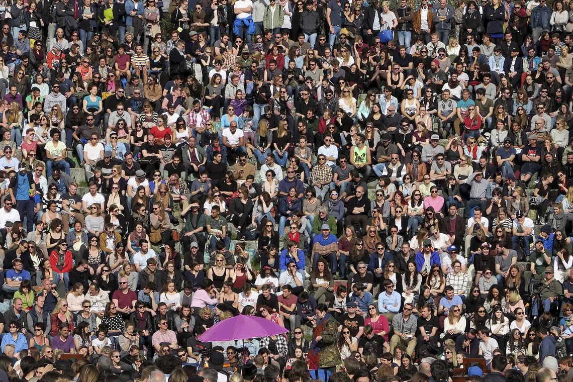 People gather as an artist performs at the Mauer Park in Berlin April 12, 2015. REUTERS/Pawel Kopczynski/ File Photo