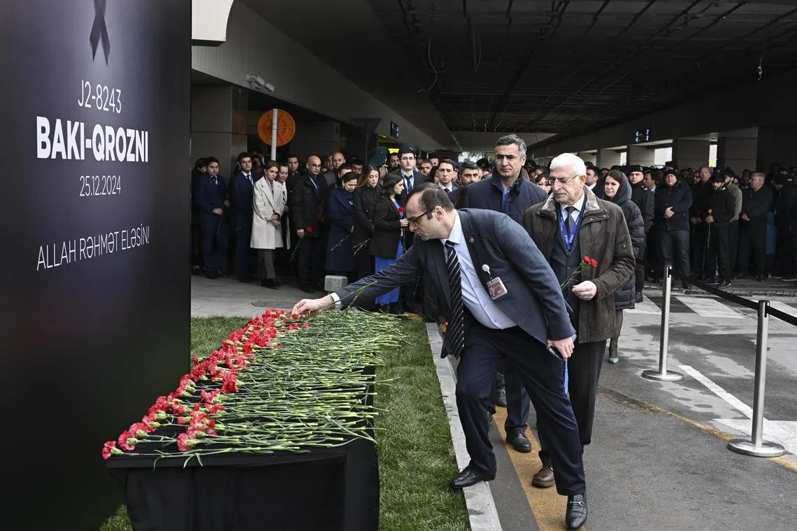 People laying flowers in memory of the victims of the Azerbaijan Airlines plane crash, at an airport outside Baku, Azerbaijan, on Dec 26.