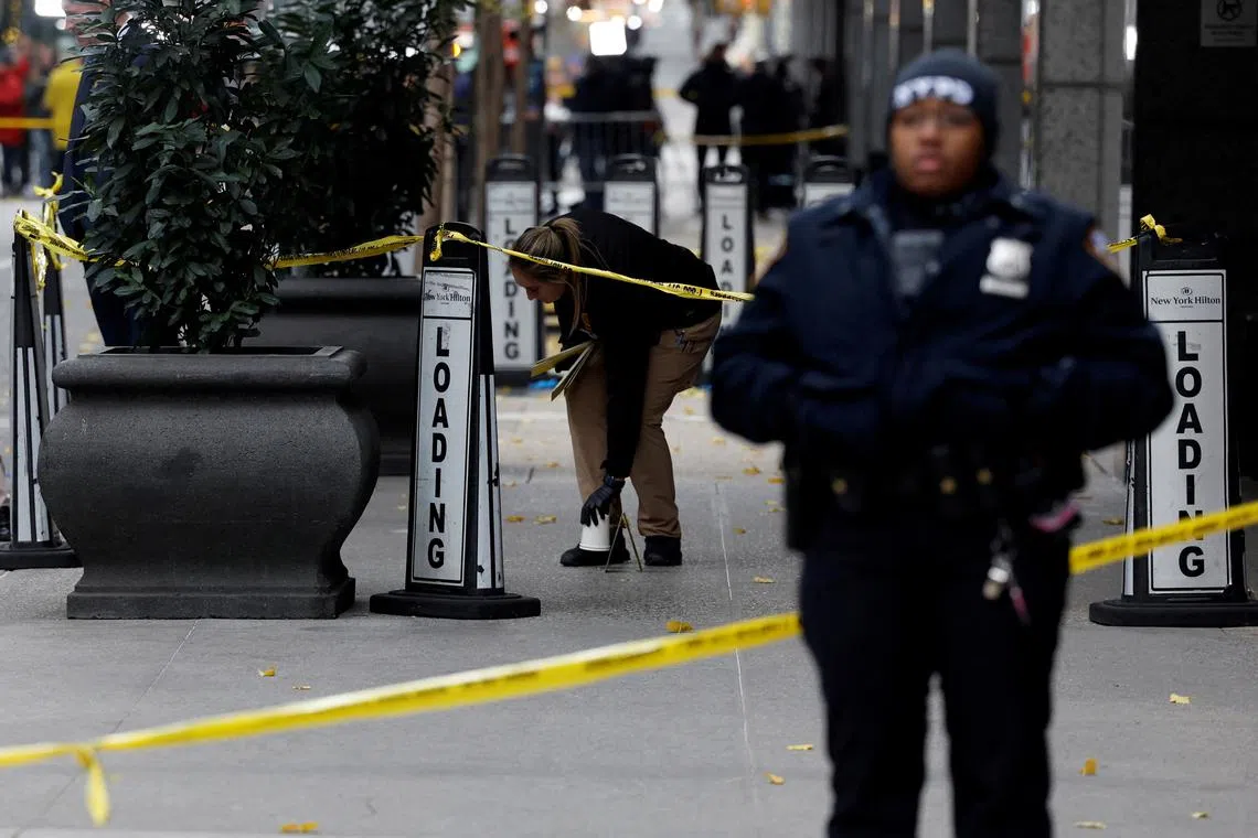 FILE PHOTO: A member of the NYPD Crime Scene Unit works near evidence markers placed where shell casings were found at the scene where the CEO of UnitedHealthcare Brian Thompson was reportedly shot and killed in Midtown Manhattan, in New York City, US, December 4, 2024.REUTERS/Shannon Stapleton/File Photo