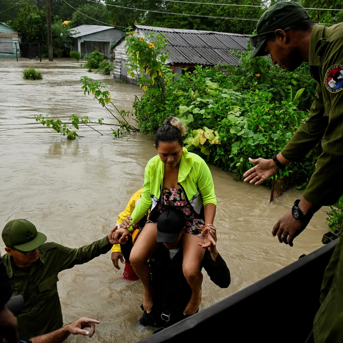 A woman is evacuated from her home by emergency personnel after the Cauto River flooded due to Hurricane Melissa, in Rio Cauto, Granma Province, Cuba October 31, 2025. REUTERS/Norlys Perez
