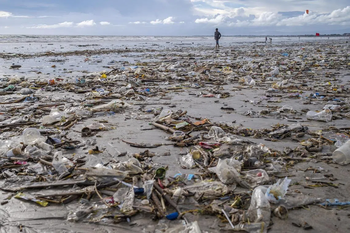 A man walks along a beach filled with waste that was washed ashore at Kuta Beach in Bali, Indonesia.