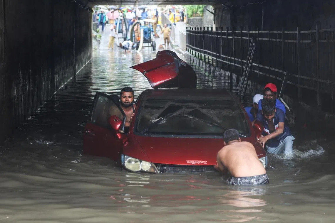 epaselect epa11466759 People push a stalled car in a water-logged underpass during heavy rain in Mumbai, India, 08 July 2024. Vehicular movements were affected and local trains were delayed due to heavy rain in the city.  EPA-EFE/DIVYAKANT SOLANKI