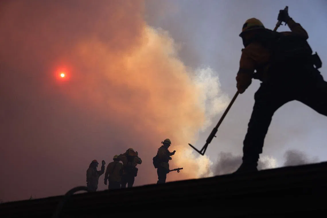 Firefighters working as a brush fire burns in Pacific Palisades, California on Jan 7, 2025. A fast-moving brushfire in a Los Angeles suburb burned buildings and sparked evacuations Tuesday as "life threatening" winds whipped the region. 