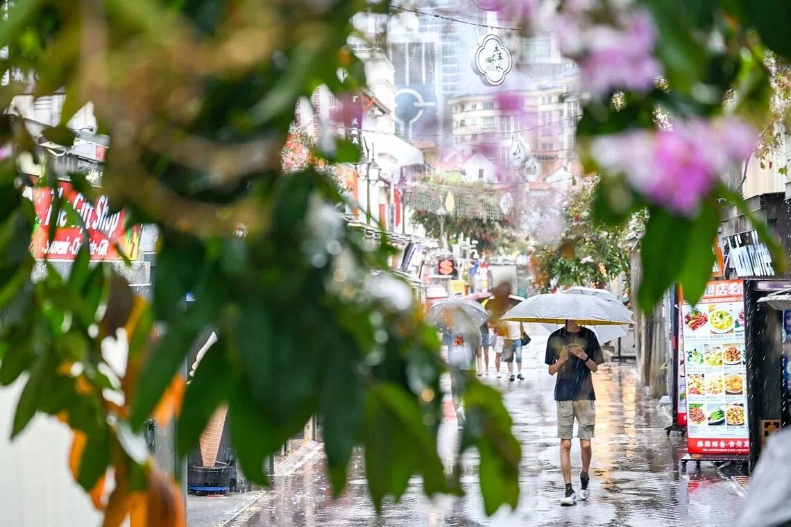 People carrying umbrellas in Singapore's Chinatown during afternoon showers on June 22.
