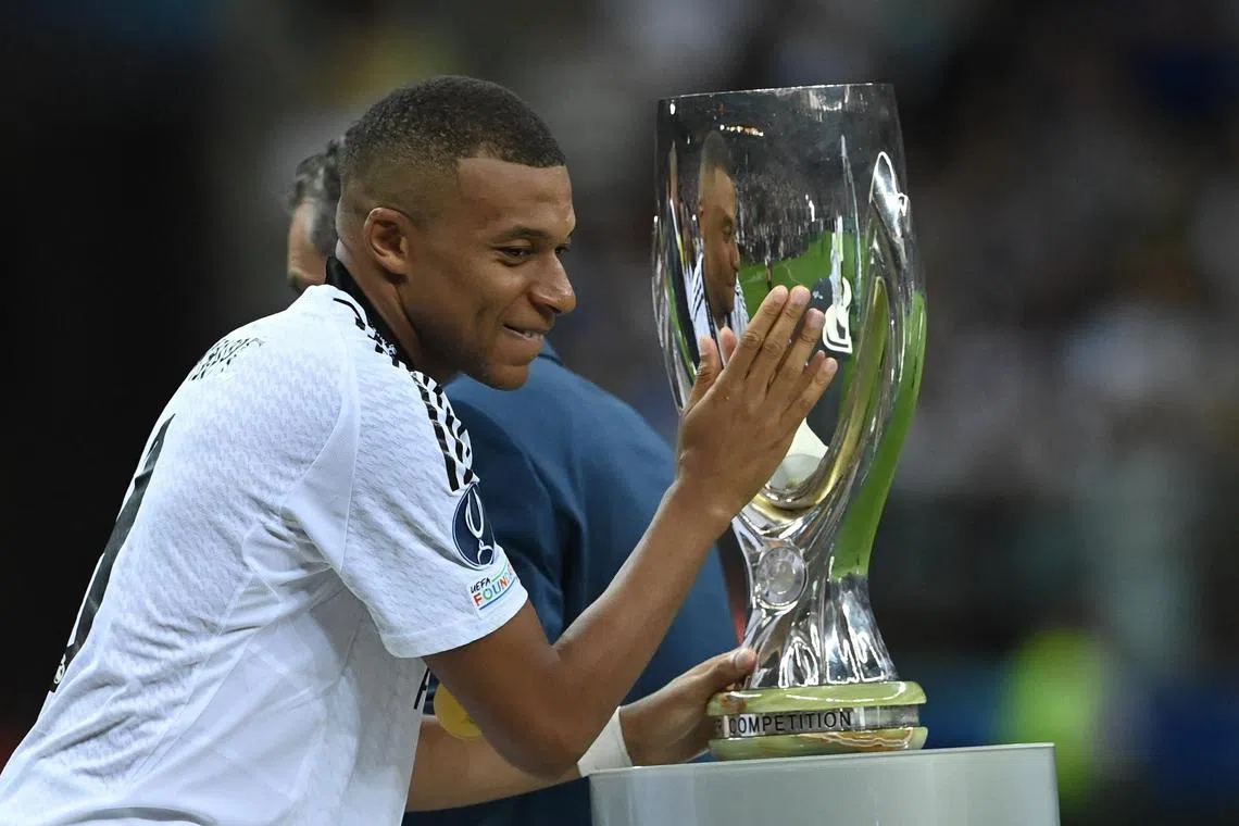 Real Madrid's Kylian Mbappe taps the trophy after receiving his Uefa Super Cup medal. He scored in their 2-0 win over  Atalanta in Warsaw on Aug 14, 2024. 