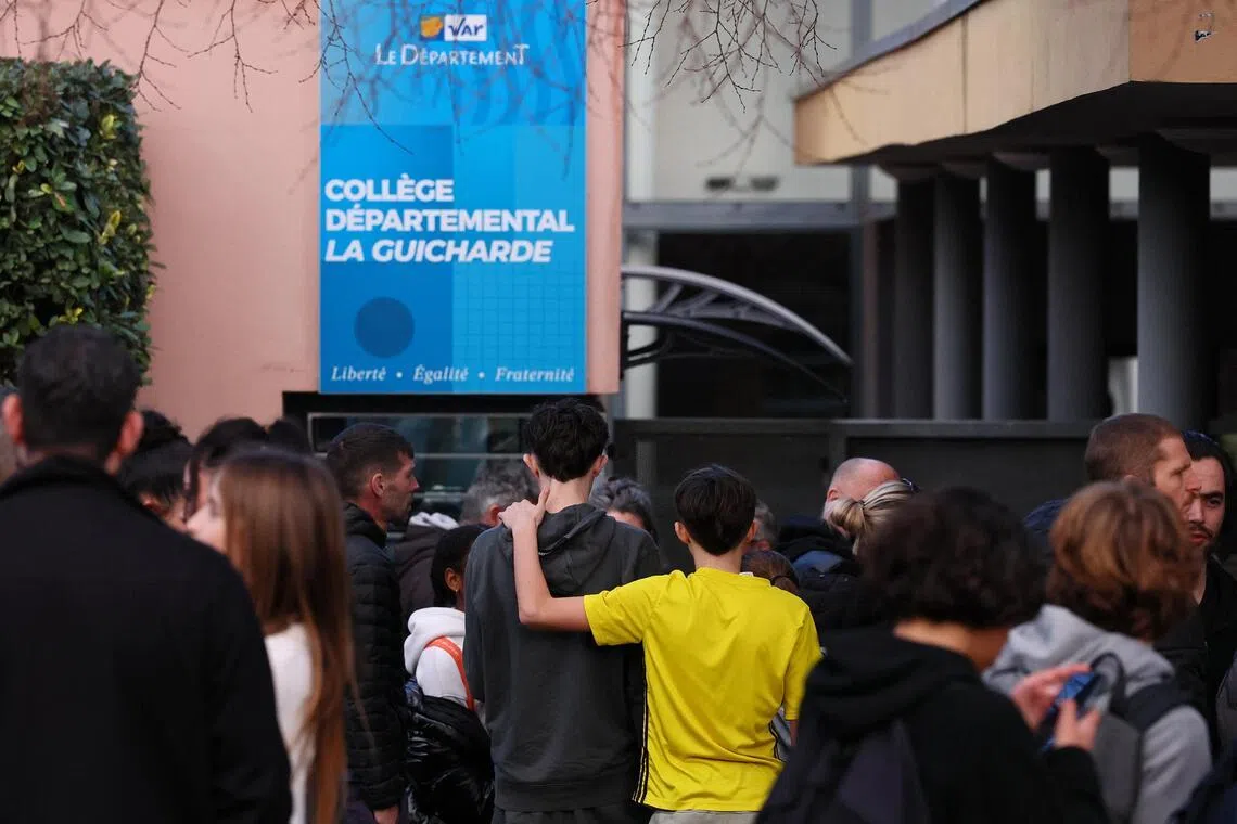 Students and their parents stand in front of the La Guicharde middle school after a teacher was seriously injured after being stabbed by a student on Feb 3.