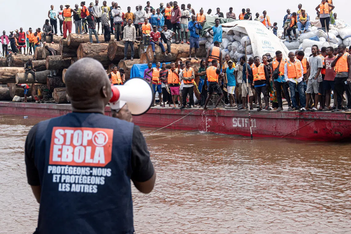 FILE PHOTO: A volunteer uses a megaphone to make announcements while intercepting a passenger boat, after, according to officials, a passenger who had disembarked earlier died after developing symptoms consistent with Ebola, in a place given as Kinshasa, Democratic Republic of the Congo, in this handout image released on August 5, 2026. International Organization For Migration/Handout via REUTERS/ File Photo