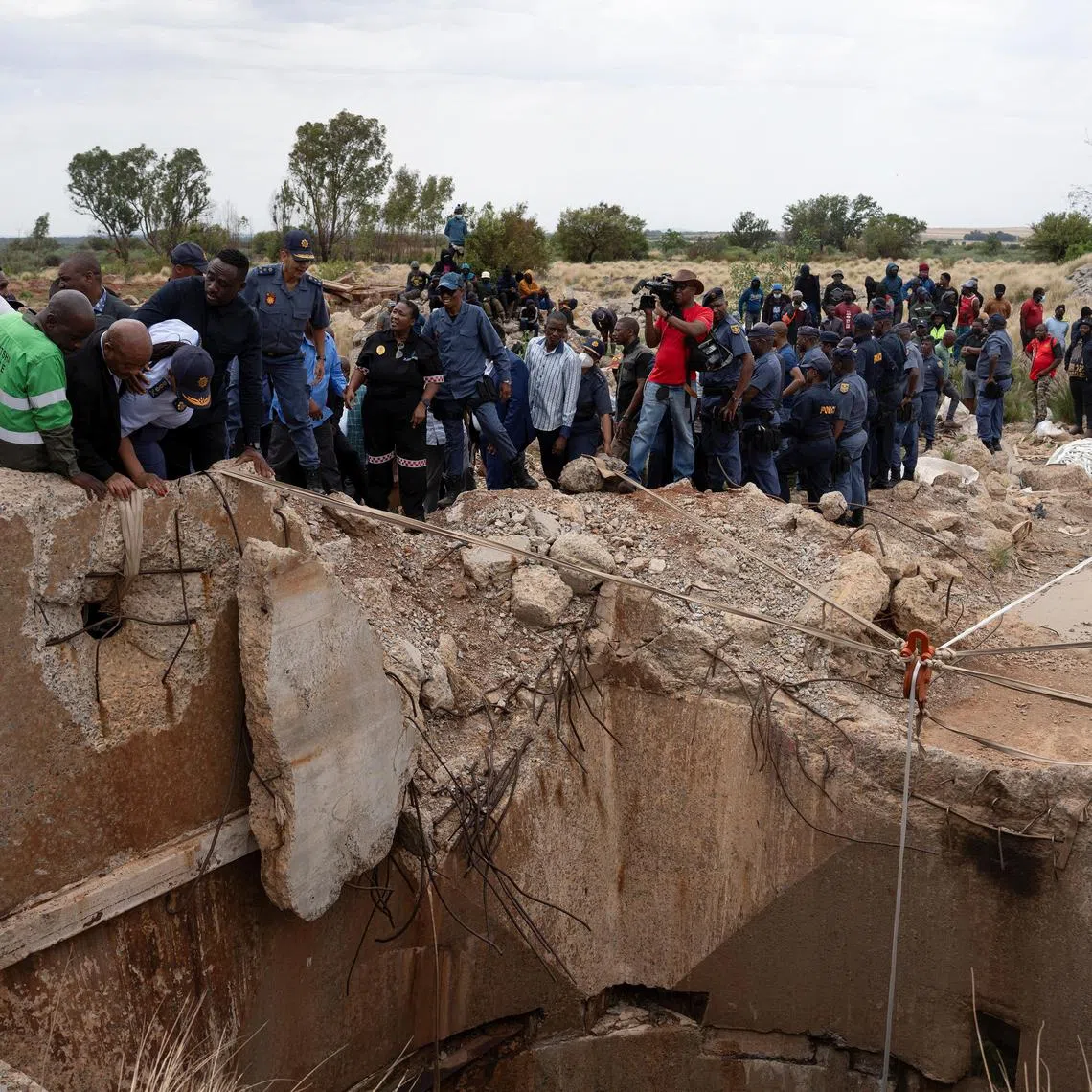 Community members watch as Mr Senzo Mchunu, South African police minister, inspects outside the mineshaft where it is estimated that hundreds of illegal miners are believed to be hiding underground in Stilfontein, South Africa, on Nov 15.