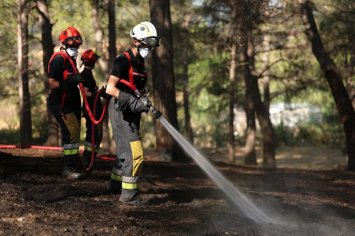 French firefighters spray water to contain a wildfire in Martigues near Marseille, France, July 18, 2025. REUTERS/Manon Cruz
