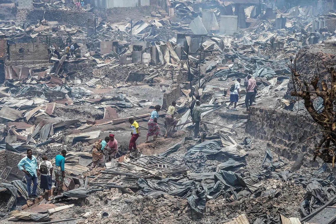 TOPSHOT - Residents walk among the debris of a fire who ravaged a school in Bukavu, on September 10, 2026. A fire broke out Thursday in a school in the eastern DR Congo city of Bukavu, causing a stampede that killed at least 14 children, local and health sources said. The blaze began while the children were in lessons, forcing some to try to escape by jumping from higher floors, a teacher told AFP. Large columns of smoke were still visible around the site of the fire at midday on Thursday, an AFP correspondent saw. (Photo by Joseph Amani Alimasi / AFP)
