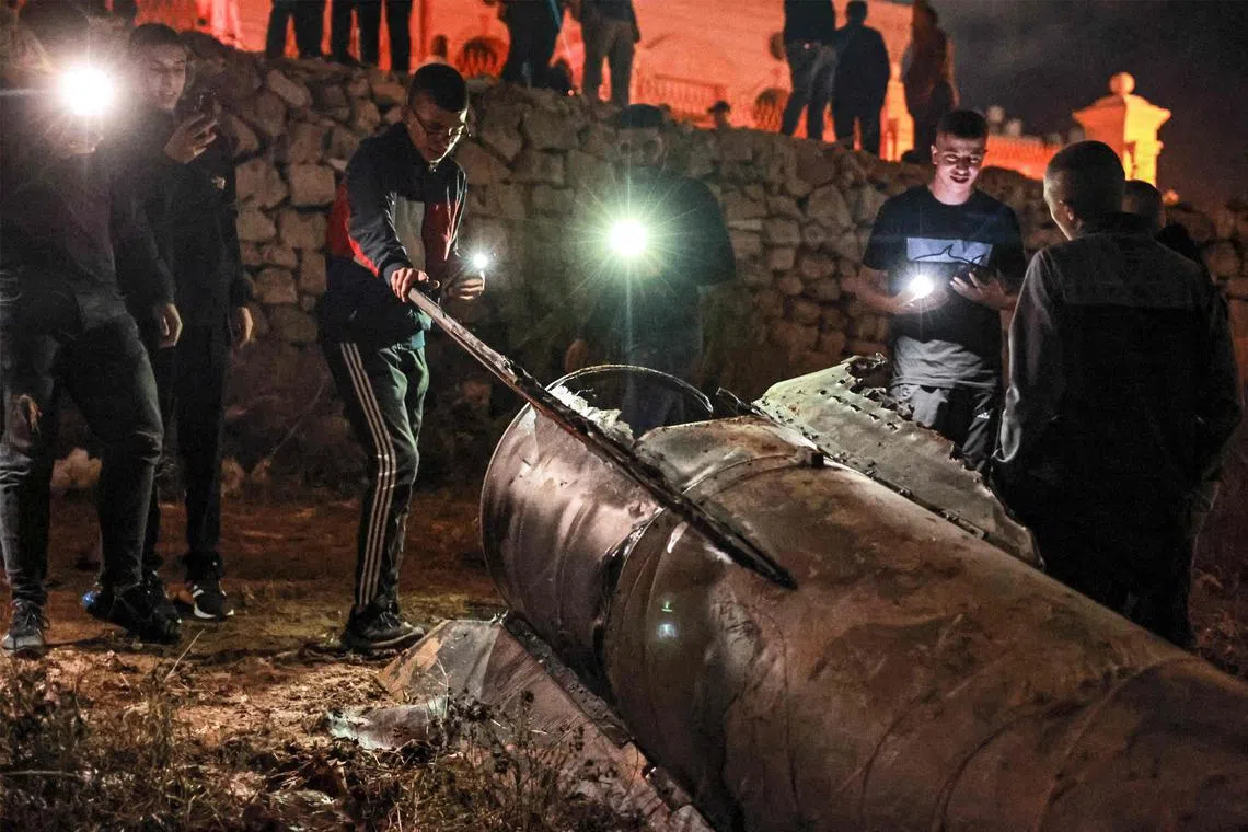 Palestinian youths in the occupied West Bank inspecting a fallen projectile on Oct 1,  after Iran launched a barrage of missiles at Israel.