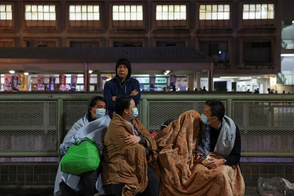 Evacuees wrapped in blankets rest on a nearby platform on Nov 26.
