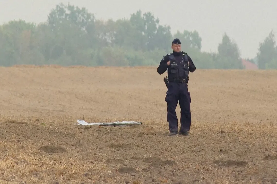 A Polish police officer stands near a drone fragment, after Russian drones violated Polish airspace on Sept 10.