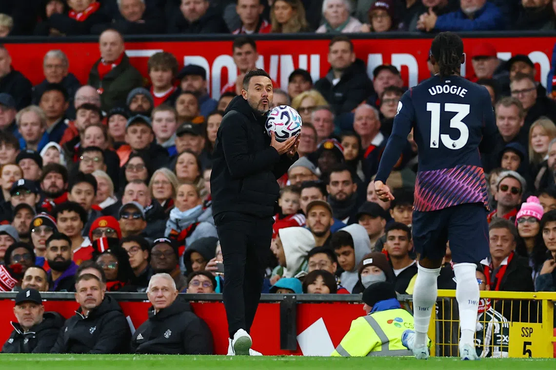 Soccer Football - Premier League - Manchester United v Tottenham Hotspur - Old Trafford, Manchester, Britain - October 10, 2026 Tottenham Hotspur manager Roberto De Zerbi holds the match ball as Destiny Udogie looks on REUTERS/Phil Noble
