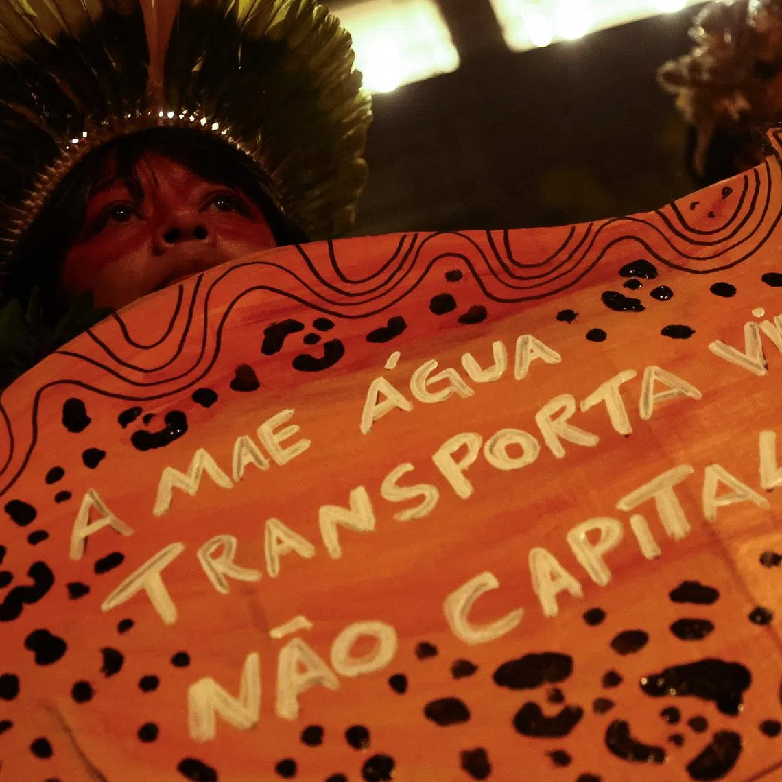 A protester shows a sign that reads \"Mother water transports life, not capitalism\" during a demonstration at Cargill's offices in support of Indigenous groups who have been blocking truck traffic for several days at the entrance of Cargill's Santarem terminal in northern Brazil, protesting against plans to dredge the Tapajos river and move more grains like soy and corn destined for export markets, in Sao Paulo, Brazil, February 20, 2026. REUTERS/Jean Carniel