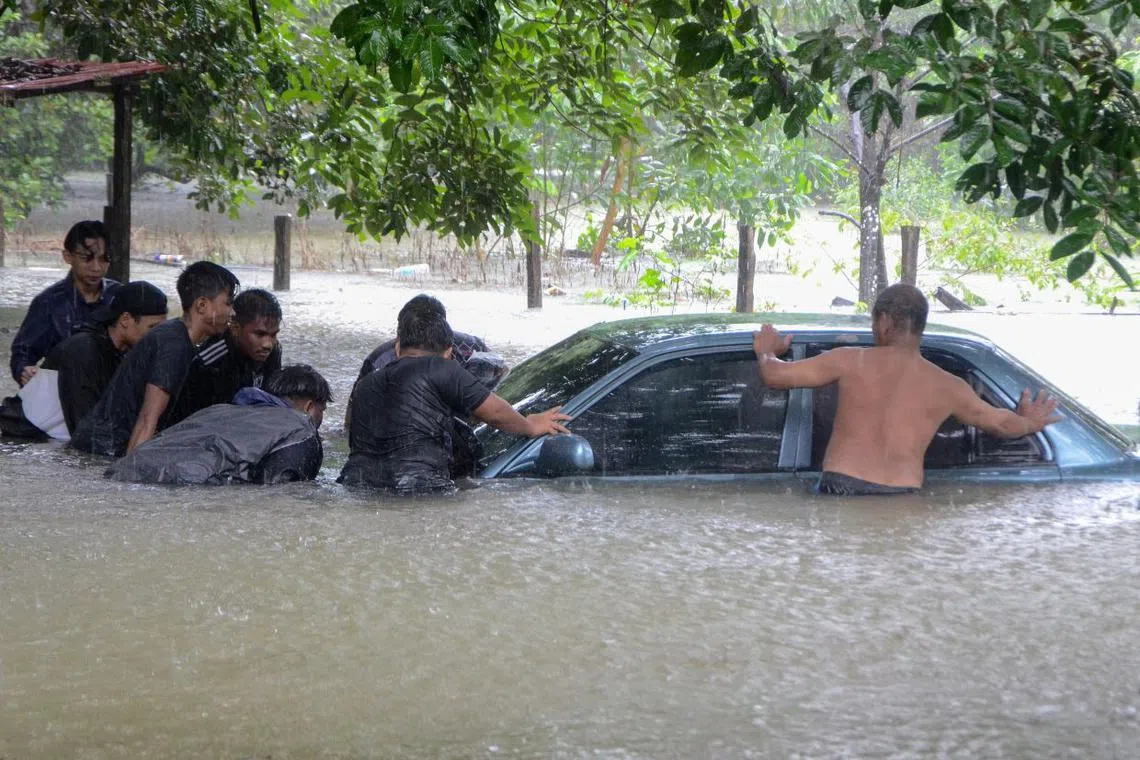 Kampung Chawas residents helped Mr Shukri Ismail push his car to higher ground as the village in Tanah Merah, Kelantan was hit by flood on Dec 18, 2022. 