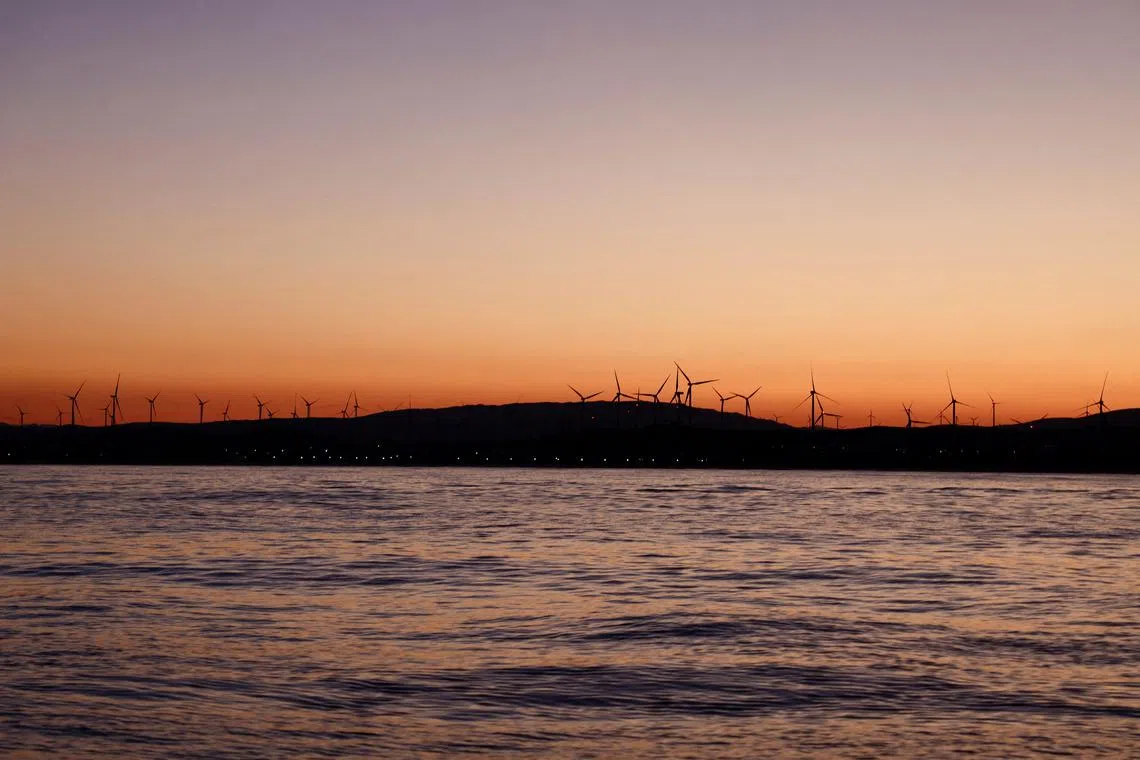 FILE PHOTO: Wind turbines spin in front of the Atlantic Ocean near Zahara de los Atunes, Spain May 27, 2025. REUTERS/Nacho Doce/ File Photo