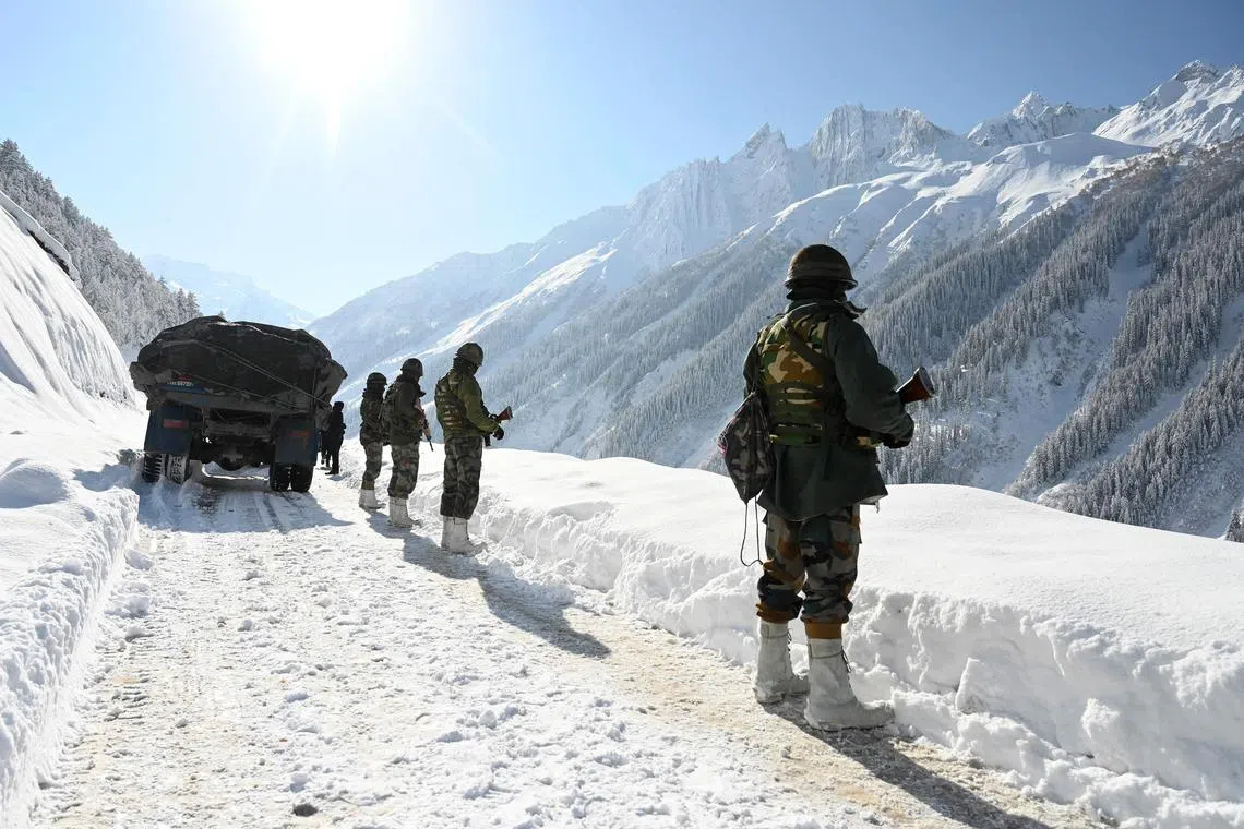 (FILES) Indian army soldiers walk along a road near Zojila mountain pass that connects Srinagar to the union territory of Ladakh, bordering China on February 28, 2021. India said on October 21, 2024 it had struck an agreement with neighbour China for military patrols in highly contested border zones, stalled since their rival armies clashed in 2020. (Photo by TAUSEEF MUSTAFA / AFP)