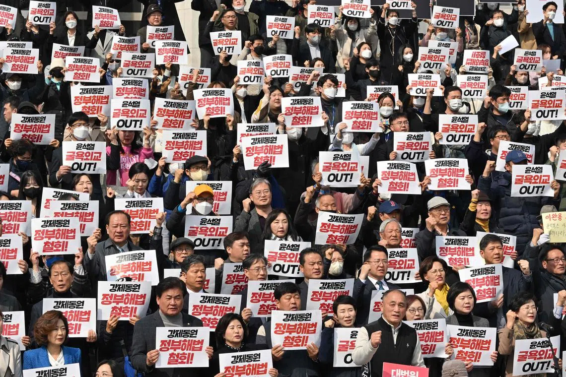 South Korean lawmakers and protesters hold placards during an anti-government rally denouncing South Korea's plans to compensate victims of Japan's forced wartime labour, at the National Assembly in Seoul on March 7, 2023. - South Koreans who were forced to work for Japanese companies like Mitsubishi during World War II on March 7, slammed Seoul's new plan to compensate them and end a historic dispute with Tokyo as "dirty money". (Photo by Jung Yeon-je / AFP)