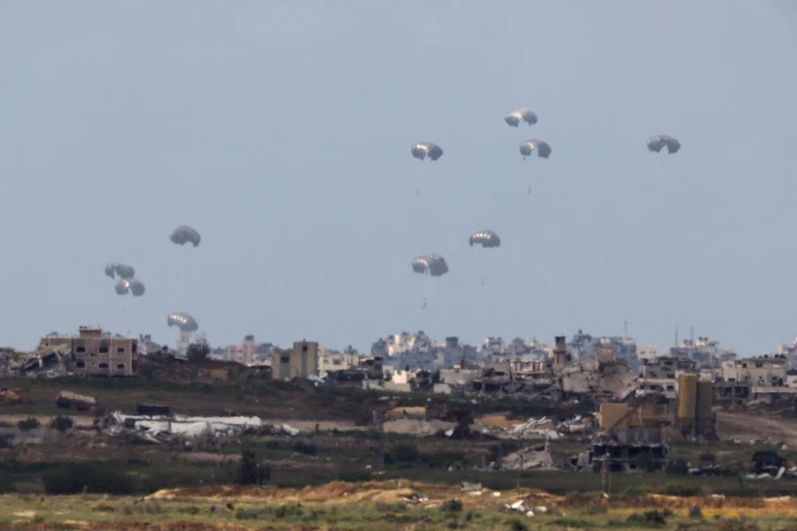 Humanitarian aid falls through the sky towards the Gaza Strip after being dropped from an aircraft, as seen from Israel, on April 10.