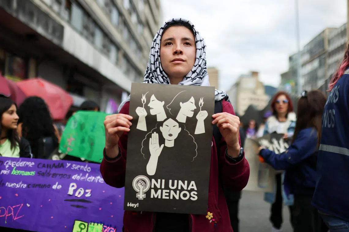 A woman holds a placard reading "Not one less", as people attend a protest in Bogota, Colombia.