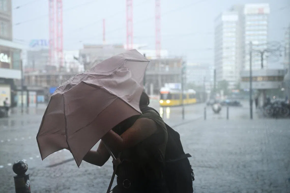 A woman shielding herself with an umbrella on a street on Alexanderplatz square during stormy weather in Berlin, Germany, on June 26, 2025. 