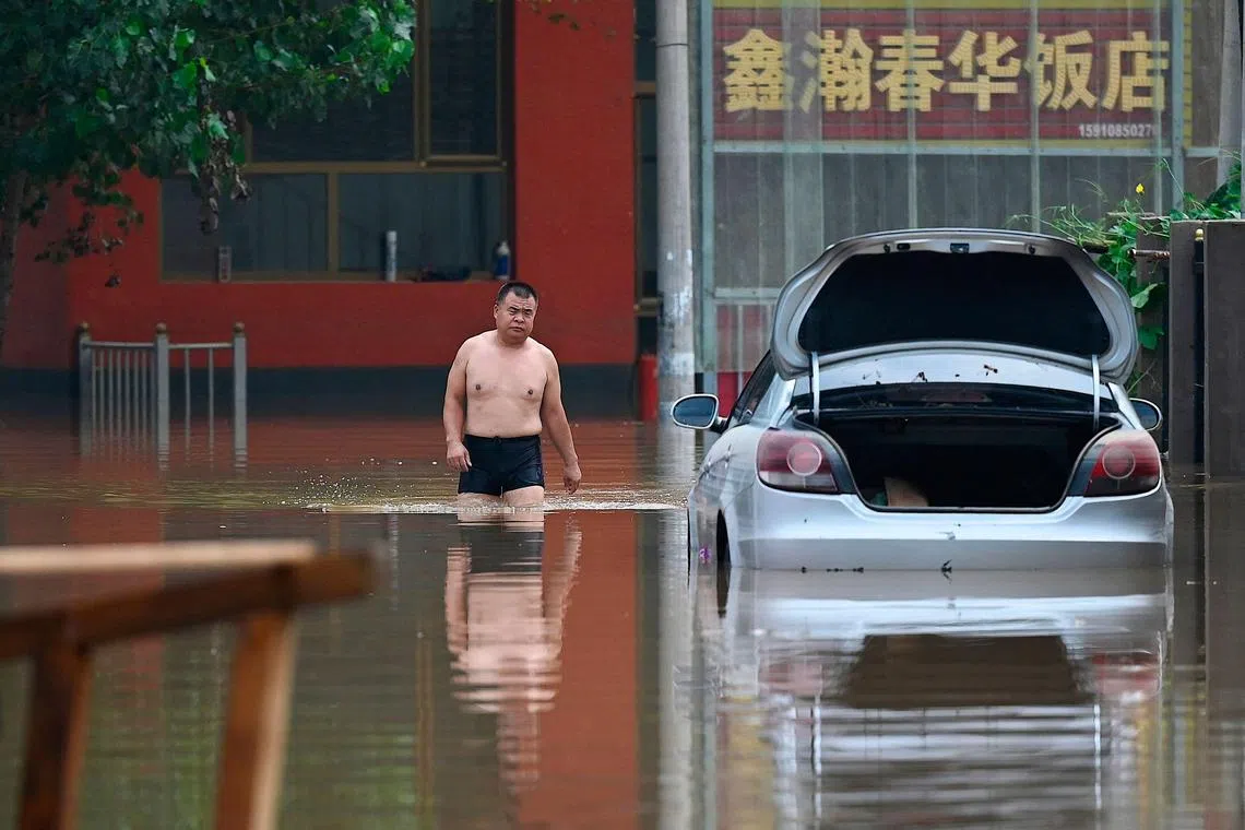 A man wadding on a flooded road following heavy rains in Zhuozhou, in northern China’s Hebei province on August 2, 2023. Deadly rains that pummelled China's capital in recent days were the heaviest since records began 140 years ago, Beijing's weather service said on August 2, as a massive cleanup operation began. 