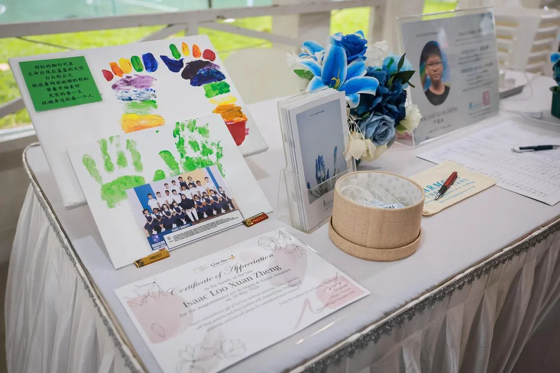 Palm prints of Issac Loo, 14, displayed on a table with his Certificate of Appreciation for his donation of organs and tissue at his wake held at a pavilion at Woodlands Circle on May 28, 2024. The prints were made with the help of his mother Madam Fiona Soo, 51, and his two brothers, on the day the doctor certified he was brain dead, before his organs transplant operation.
