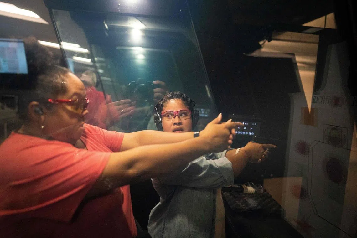 Chakiar Trotman (right), of Tenleytown, pointing a firearm down range, looks back at Charneta Samms as she and other members of the A Girl & A Gun women’s shooting league use a firing range at Guntry in Owings Mills, Maryland, on Sept 27. 