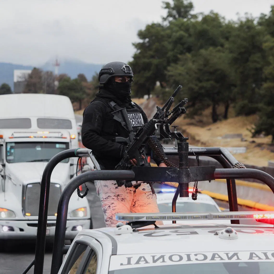 A member of the National Guard stands on a vehicle at the site on the highway connecting Mexico City with the state of Puebla, where unknown assailants torched a bus and a trailer, following roadblocks and arson attacks carried out by members of organized crime in several states after a military operation in which a government source said Mexican drug lord Nemesio Oseguera, known as \"El Mencho,\" was killed in Jalisco state, in Santa Rita Tlahuapan, Mexico, February 22, 2026. REUTERS/Paola Garcia