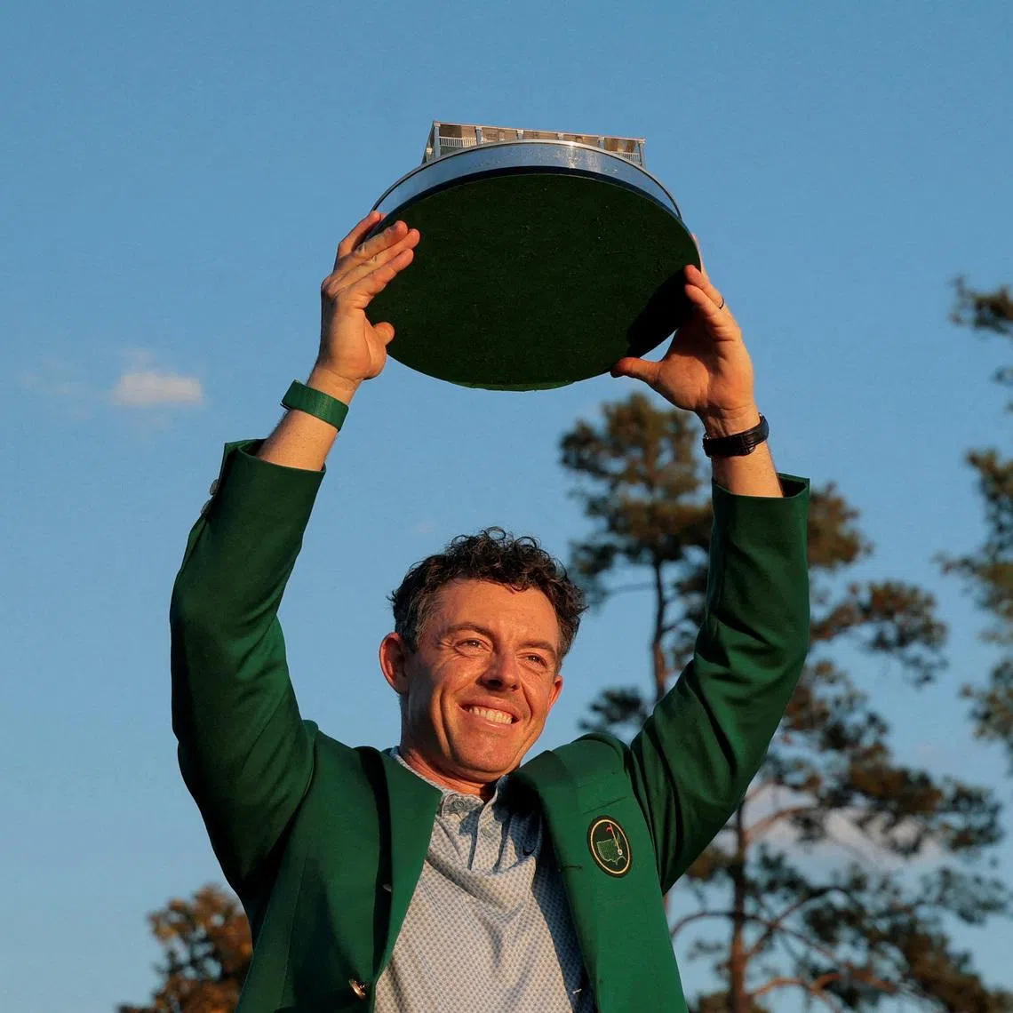 Golf - The Masters - Augusta National Golf Club, Augusta, Georgia, U.S. - April 12, 2026 Northern Ireland's Rory McIlroy celebrates with his green jacket and the trophy after winning The Masters REUTERS/Brian Snyder