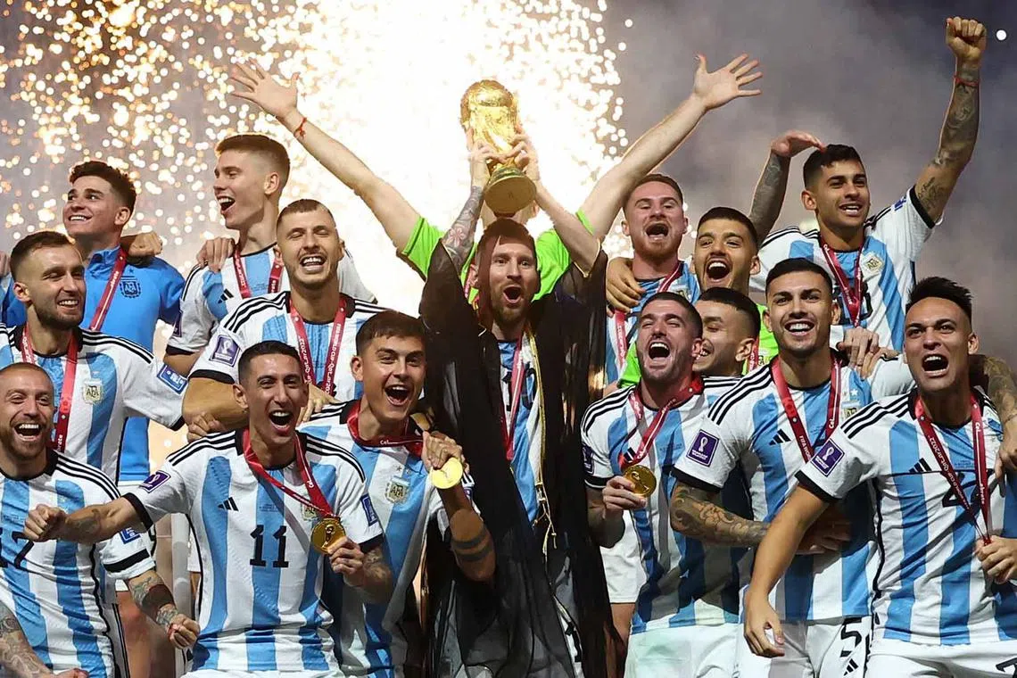 Argentina's Lionel Messi lifts the World Cup trophy alongside teammates as they celebrate after winning the World Cup.