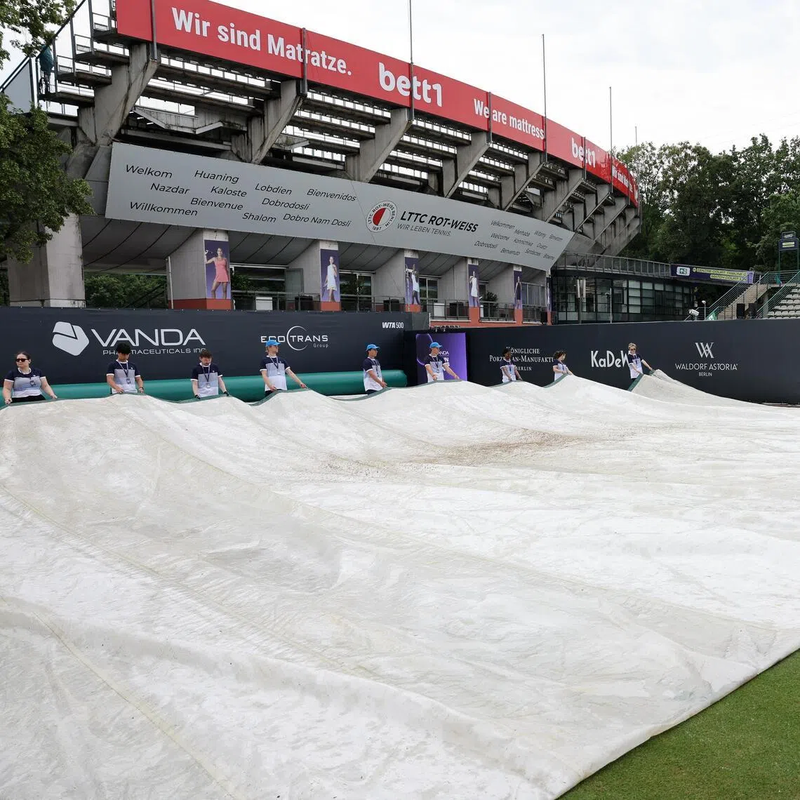 Staff take tarpaulin off of the court at the Steffi Graf Stadium, site of the WTA Berlin Open on June 21, 2026. The final has been suspended due to “severe weather conditions”.