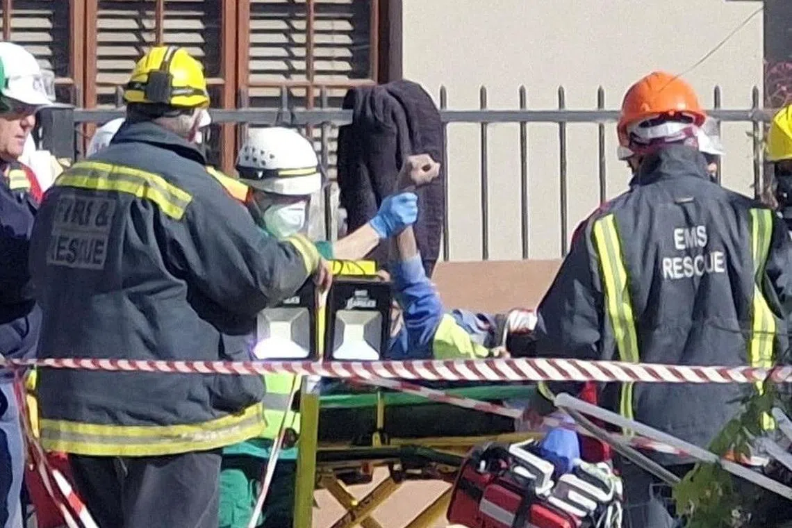 A survivor raises his hand after 116 hours under the debris of the collapsed building, as rescue workers carry him to an ambulance.