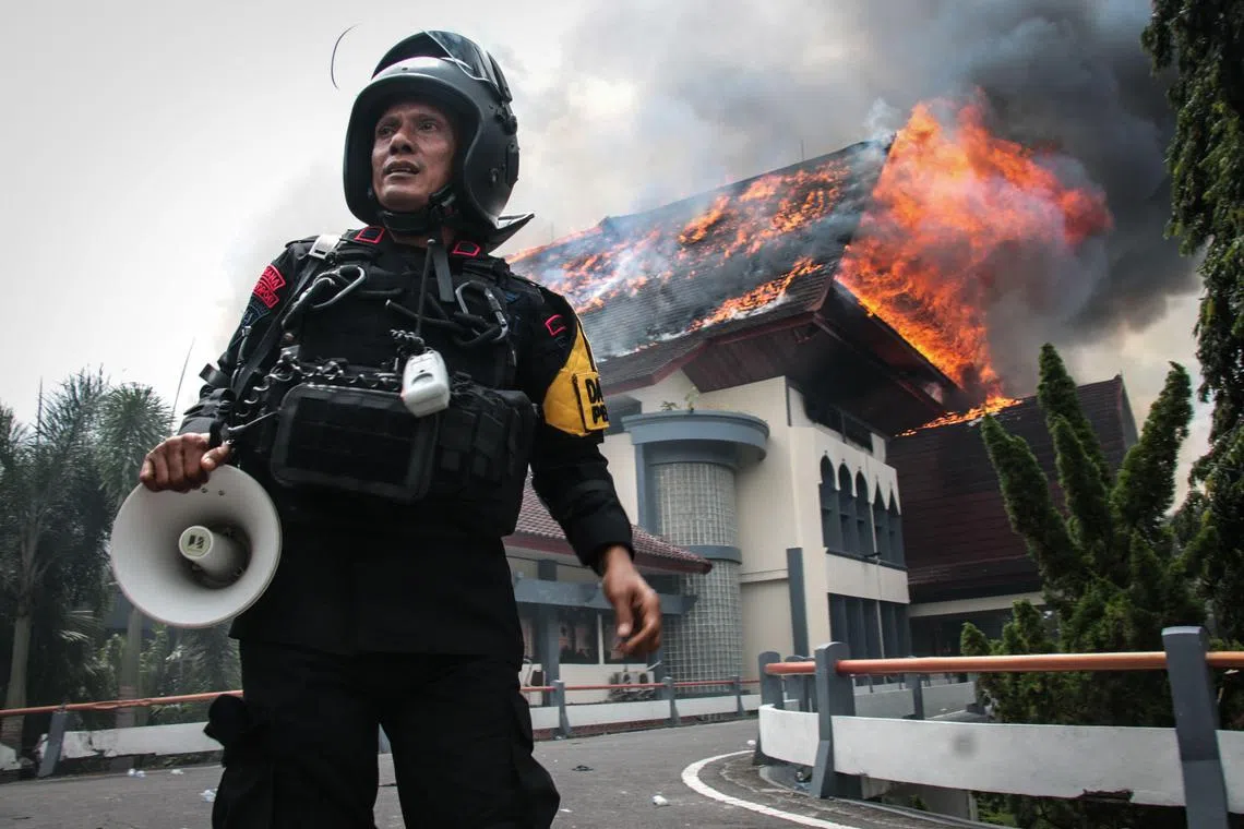 A police officer standing near the West Nusa Tenggara Provincial Council office on Indonesia's Lombok island after protesters set it ablaze on Aug 30.