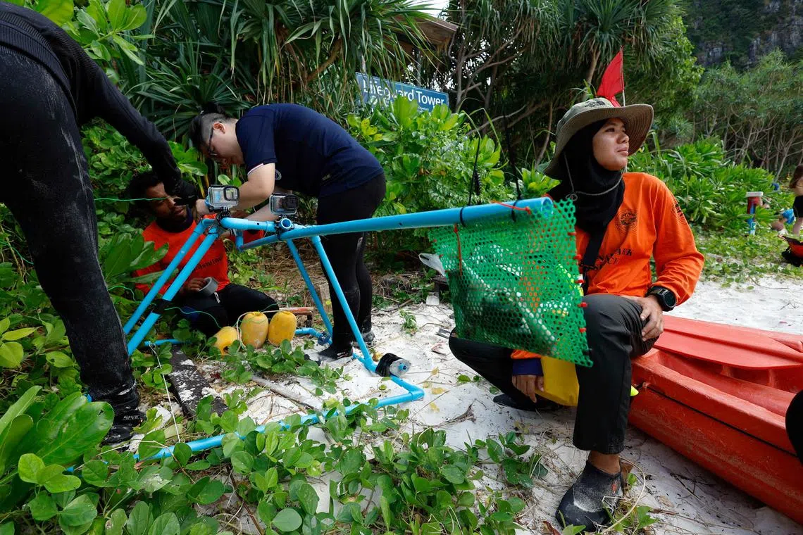 Sommawan Kasa, 29, Metavee Chuangcharoendee, 27, and Jampon Khonthong, 38, team members of the Maya Shark Watch Project, prepare to install their baited remote underwater video station in Maya Bay at the Phi Phi Island National Park on Feb 23, 2023. The Maya Shark Watch Project uses underwater cameras and drones to count sharks and observe their behaviour, feeding areas, and breeding patterns. 