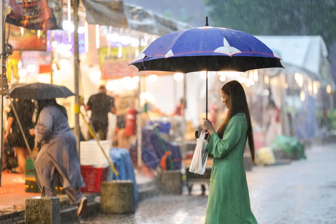 Lady walking in the rain outside Woodlands MRT on Jan 10, 2025. 