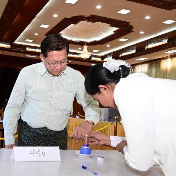 A polling official assists Myanmar's junta chief Min Aung Hlaing during voting at Zayarthiri polling station, on the day of the general elections in Naypyitaw, Myanmar, December 28, 2025. Myanmar Military Information Team/Handout via REUTERS