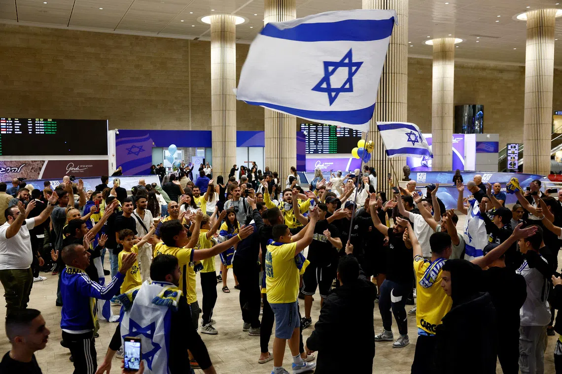 People celebrate as Maccabi Tel Aviv soccer fans arrive at the Ben Gurion International Airport, after overnight attacks after the match between Maccabi and Ajax Amsterdam, in Lod, Israel, November 8, 2024. REUTERS/Thomas Peter/File Photo