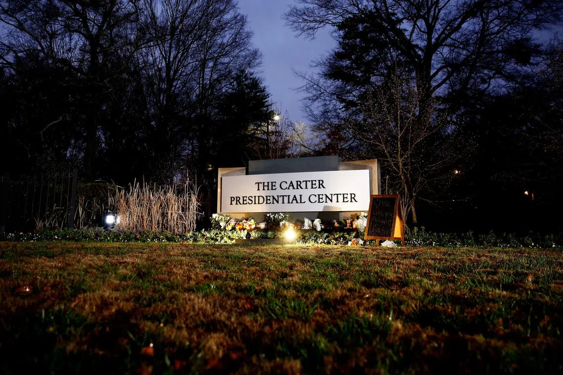 Flowers and mementos rest by the sign of The Carter Presidential Center, paying tribute to the life and legacy of former U.S. President Jimmy Carter, who passed away at the age of 100, in Atlanta, Georgia, U.S. December 30, 2024.  REUTERS/Octavio Jones