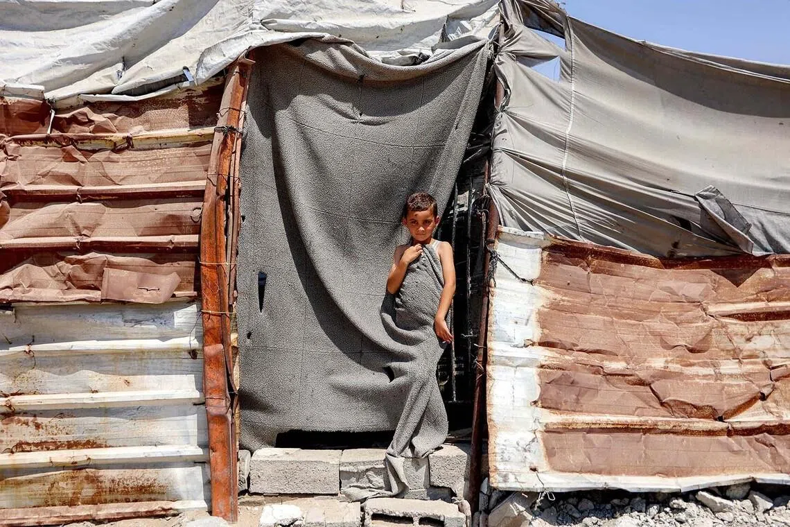 TOPSHOT - A boy stands at the entrance of a tent at a camp for people displaced by war in the Sheikh Radwan neighbourhood of Gaza City on July 6, 2026. The Palestinian Islamist movement Hamas announced on July 6 the dissolution of the body that has governed the Gaza Strip for nearly two decades, clearing the way for a technocratic committee to implement civilian rule. Since a ceasefire took effect in Gaza last October between Hamas and Israel, the group has repeatedly said it is prepared to step aside from day-to-day governance, but the thorny issue of its disarmament remains unresolved. (Photo by Omar AL-QATTAA / AFP)