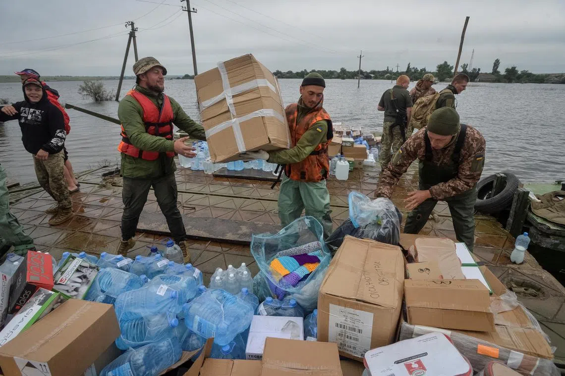 Ukrainian servicemen unload humanitarian aid for local residents, in the flooded village of Afanasiivka, in Ukraine's Kherson region.