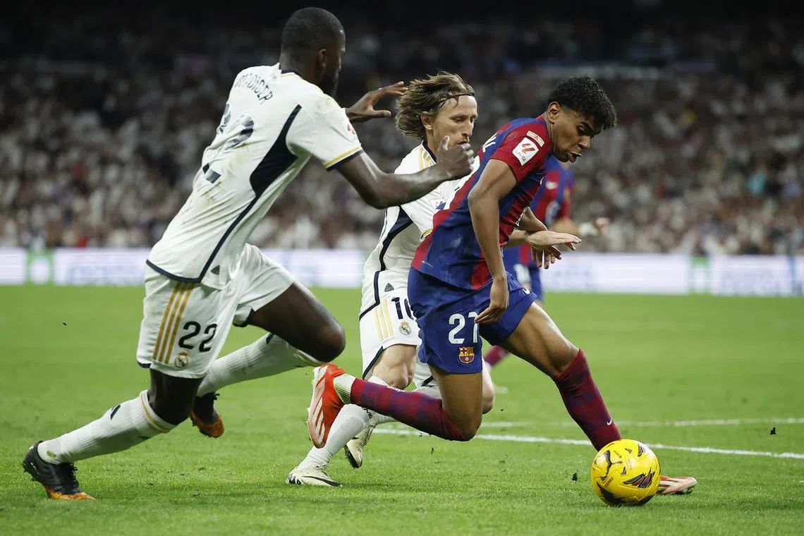 Soccer Football - LaLiga - Real Madrid v FC Barcelona - Santiago Bernabeu, Madrid, Spain - April 21, 2024 FC Barcelona's Lamine Yamal in action with Real Madrid's Antonio Rudiger and Luka Modric REUTERS/Juan Medina