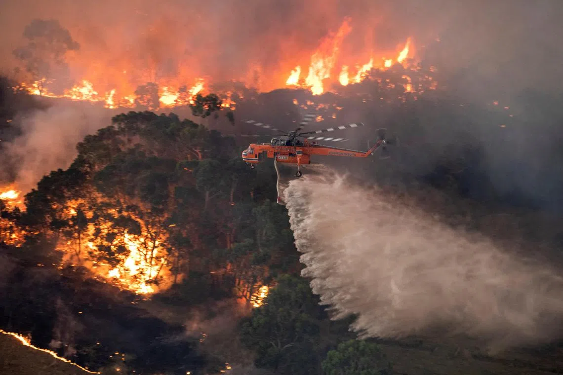 A handout photo taken and received on December 31, 2019 from the State Government of Victoria shows a helicopter fighting a bushfire near Bairnsdale in Victoria's East Gippsland region. Thousands of holidaymakers and locals were forced to flee to beaches in fire-ravaged southeast Australia on December 31, as blazes ripped through popular tourist areas leaving no escape by land. (Photo by Handout / STATE GOVERNMENT OF VICTORIA / AFP) / RESTRICTED TO EDITORIAL USE - MANDATORY CREDIT "AFP PHOTO / STATE GOVERNMENT OF VICTORIA" - NO MARKETING NO ADVERTISING CAMPAIGNS - DISTRIBUTED AS A SERVICE TO CLIENTS
