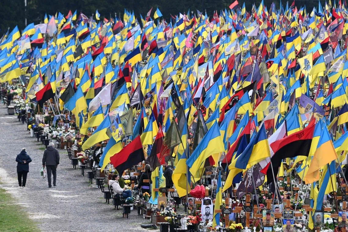 TOPSHOT - People visit the graves of fallen Ukrainian soldiers at the Lychakiv Military Cemetery during Orthodox Easter celebrations in Lviv on April 12, 2026, amid the Russian invasion of Ukraine. (Photo by YURIY DYACHYSHYN / AFP)