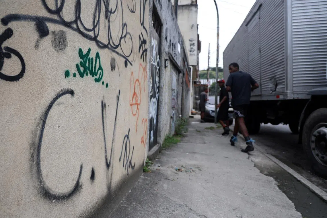 People walk past graffiti reading \"C.V\", referring to a Brazilian gang Comando Vermelho, in Penha neighborhood in Rio de Janeiro, Brazil May 29, 2026. REUTERS/Aline Massuca