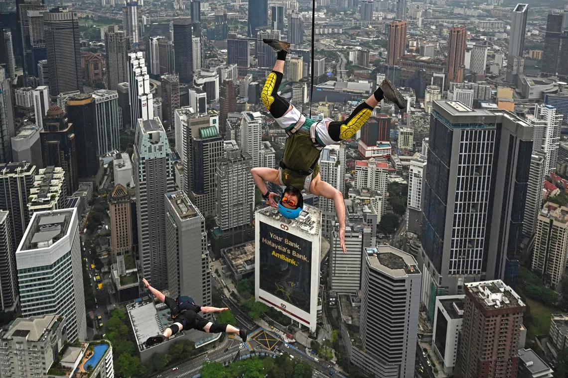Base jumper Sean Devlin of the US (R) leaps from the 300-metre high open deck of Malaysia's landmark Kuala Lumpur Tower during the International Tower Jump in Kuala Lumpur on Feb 3, 2023. 