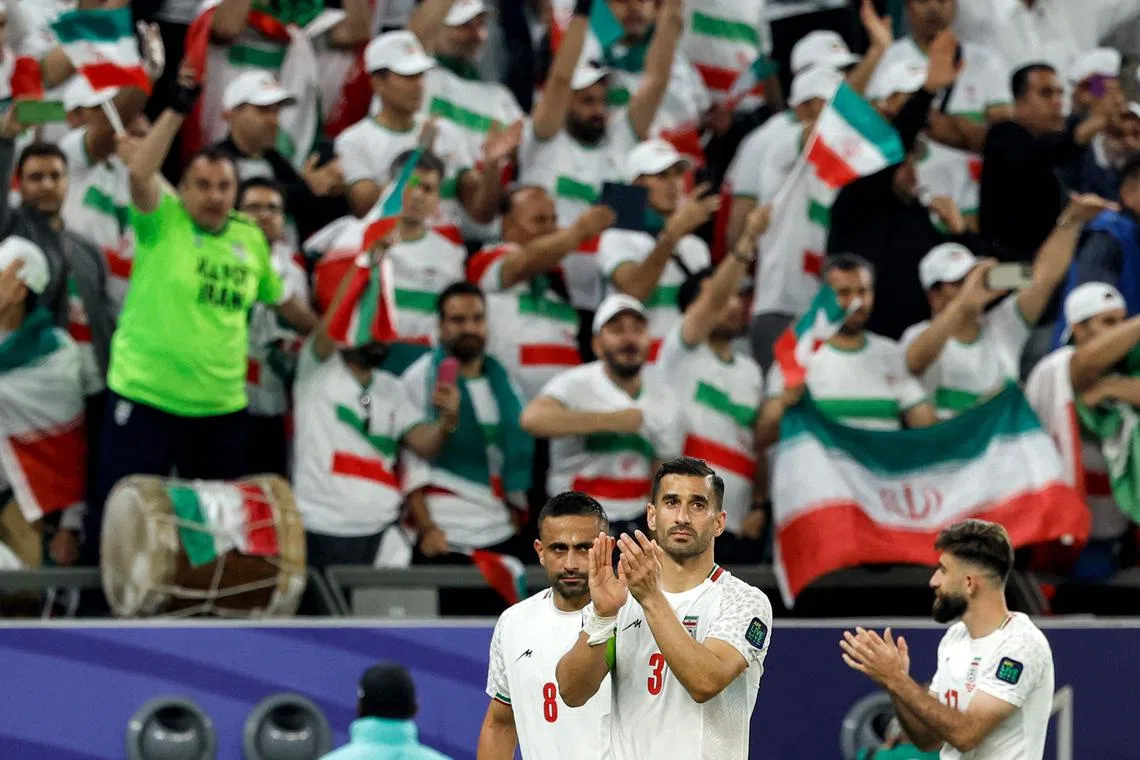 Iran's midfielder Omid Ebrahimi, defender  Ehsan Hajsafi and midfielder Ali Gholizadeh salute supporters after the match.